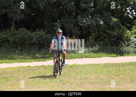 Mann in den Siebzigern mit dem Fahrrad durch den Nonsuch Park Surrey England Stockfoto