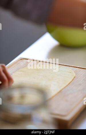 Eine vertikale Aufnahme mit selektivem Fokus eines Teiges auf einem Schneidebrett Stockfoto