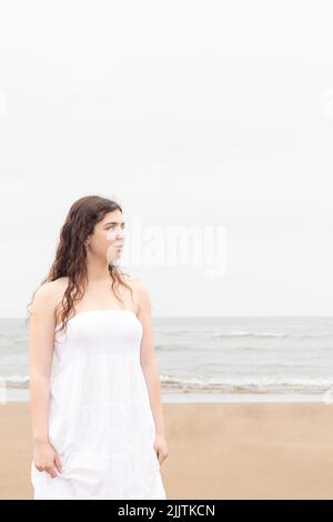 Junge Frau in einem weißen Kleid am Strand Stockfoto