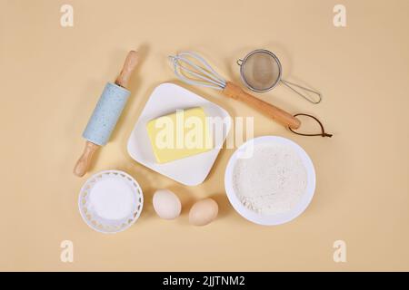 Backzutaten und Backwerkzeuge auf beigefarbenem Hintergrund Stockfoto