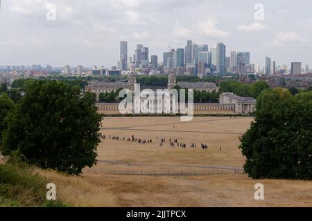 London, Greater London, England, Juli 20 2022: Universität, Queens House und Canary Wharf im Hintergrund, vom Greenwich Park aus gesehen. Stockfoto