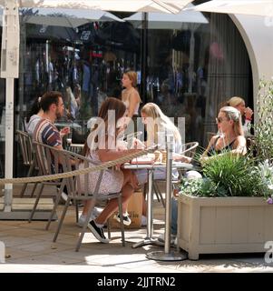 An einem sonnigen Samstag im Juli genießen die Menschen das Mittagessen in einem Restaurant auf dem Duke of York Square Stockfoto