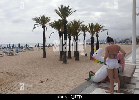 Benidorm, Spanien. 27.. Juli 2022. Urlauber tragen ein aufblasbares Einhorn am Strand von Benidorm, Spanien. Quelle: Isabel Infantes/Alamy Stockfoto