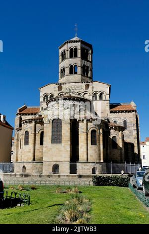 Eine vertikale Aufnahme der Abteikirche von Saint-Austremoine mit einem grasbewachsenen Hof im Vordergrund Stockfoto