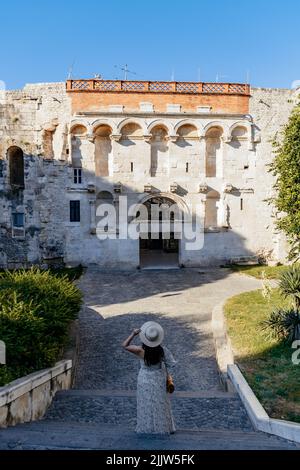 Eine Rückansicht einer Frau, die vor den goldenen Toren des Diokletianpalastes in Split, Kroatien, steht Stockfoto