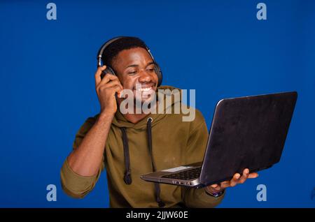 afroamerikanischer Mann, der gute Musik in Kopfhörern mit geschlossenen Augen genießt, junger schwarzer Gelegenheitsklässler, der Lieblingsmusik aus dem Jahr mp3 auf dem Laptop hört Stockfoto