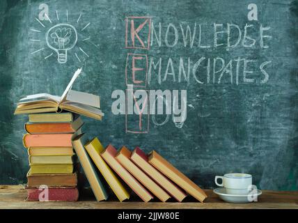 Bücher und Tafel mit Zeichnung einer Glühbirne und Slogan Wissen emanzipiert Sie,Lernen,Bildung,zurück zur Schule Konzept Stockfoto