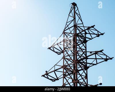 Verlassene elektrische Stange gegen den Himmel. Rostiger elektrischer Mast ohne Drähte. Stockfoto