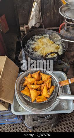 Knusprige und würzige Samosa-Snacks goldbraun in der Farbe, frisch in heißem, kochendem Öl im Lebensmittelgeschäft zubereitet Stockfoto