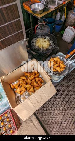 Knusprige und würzige Samosa-Snacks goldbraun in der Farbe, frisch in heißem, kochendem Öl im Lebensmittelgeschäft zubereitet Stockfoto