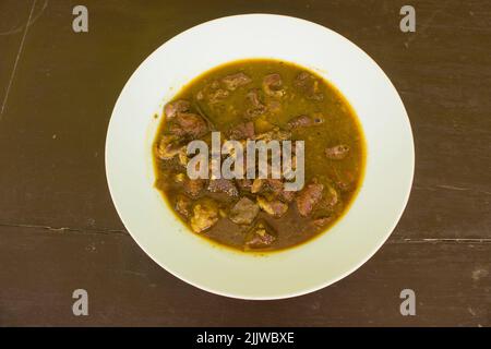 Rawon oder Nasi Rawon oder Rawon Ris ist eine stark schmeckende, traditionelle, indonesische Rindersuppe, die mit Sprossen, gesalzenen Eiern und Kluwek-Gewürzen serviert wird. Stockfoto