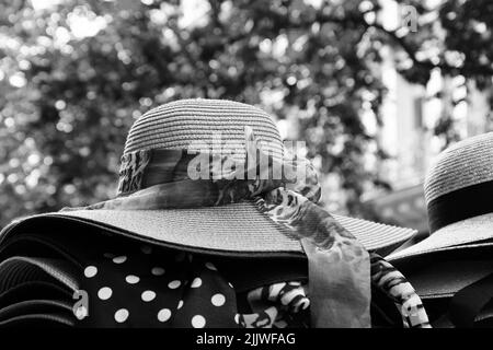 Weibliche Korbhüte mit verschiedenen Schleifen zum Verkauf. Paris, Frankreich. Retro Mode Hintergrund. Sommerurlaub, Strandurlaub Entspannung. Schwarz-weiß Stockfoto