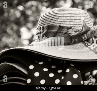 Weibliche Korbhüte mit verschiedenen Schleifen zum Verkauf. Paris, Frankreich. Retro Mode Hintergrund. Sommerurlaub, Strandurlaub Entspannung. Sepia-Foto Stockfoto