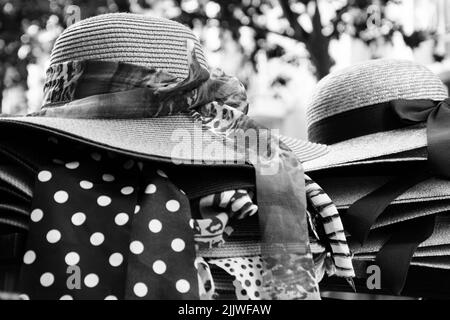 Weibliche Korbhüte mit verschiedenen Schleifen zum Verkauf. Paris, Frankreich. Retro Mode Hintergrund. Sommerurlaub, Strandurlaub Entspannung. Schwarz-weiß Stockfoto