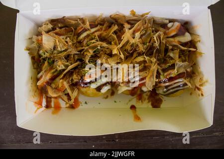 Takoyaki ist Food Japan, in Form von kleinen Kugeln aus Teigmehl mit Stücken von Oktopus gefüllt gemacht. japanisches Essen, in Holz Hintergrund isoliert Stockfoto