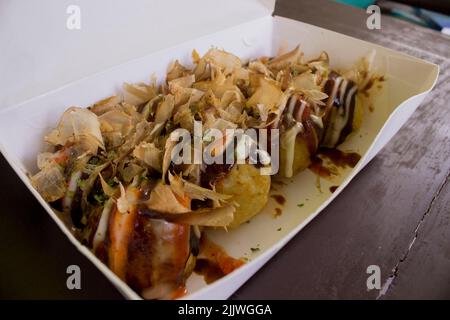 Takoyaki ist Food Japan, in Form von kleinen Kugeln aus Teigmehl mit Stücken von Oktopus gefüllt gemacht. japanisches Essen, in Holz Hintergrund isoliert Stockfoto