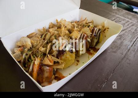 Takoyaki ist Food Japan, in Form von kleinen Kugeln aus Teigmehl mit Stücken von Oktopus gefüllt gemacht. japanisches Essen, in Holz Hintergrund isoliert Stockfoto