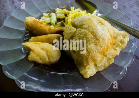 Empek-Empek ist gebratener Fisch und Tapioka, Gurkenscheiben, gelbe Nudeln mit süß-saurer Sauce namens Essigsauce oder Essigsauce serviert. Serviert Stockfoto