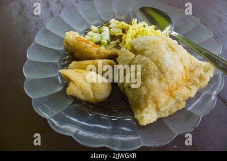 Empek-Empek ist gebratener Fisch und Tapioka, Gurkenscheiben, gelbe Nudeln mit süß-saurer Sauce namens Essigsauce oder Essigsauce serviert. Serviert Stockfoto