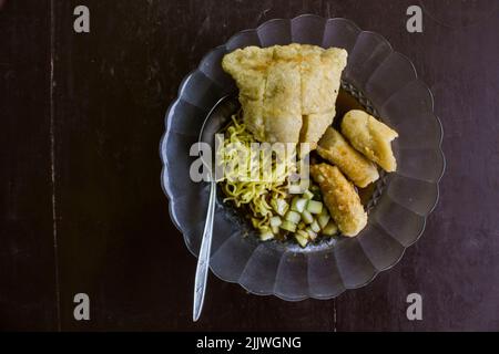 Empek-Empek ist gebratener Fisch und Tapioka, Gurkenscheiben, gelbe Nudeln mit süß-saurer Sauce namens Essigsauce oder Essigsauce serviert. Serviert Stockfoto