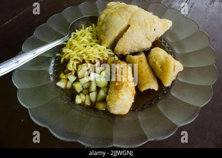 Empek-Empek ist gebratener Fisch und Tapioka, Gurkenscheiben, gelbe Nudeln mit süß-saurer Sauce namens Essigsauce oder Essigsauce serviert. Serviert Stockfoto