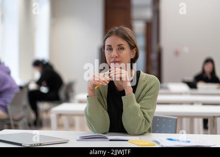 Porträt einer nachdenklichen fokussierten Frau mittleren Alters reifen weiblichen Studentin in Bibliothek Innenraum Stockfoto