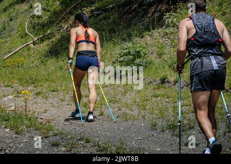 Frau und Mann gehen mit Trekkingstöcken bergauf Stockfoto