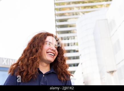 Glückliche junge Frau schaut weg, während sie in der Stadt steht Stockfoto