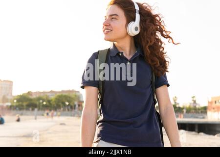 Porträt einer lächelnden jungen Frau mit einem Headset, das in der Stadt steht Stockfoto
