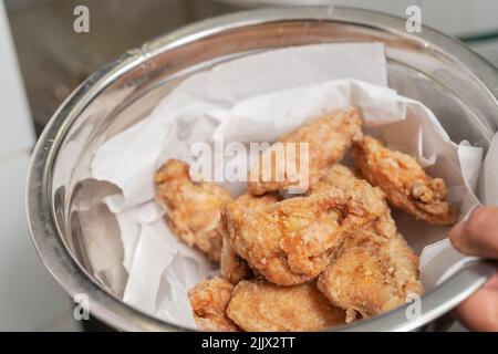 Von oben der Ernte gesichtslosen Koch mit Schüssel von leckeren gebratenen Hähnchenflügel beim Kochen in der hellen Küche des Restaurants Stockfoto