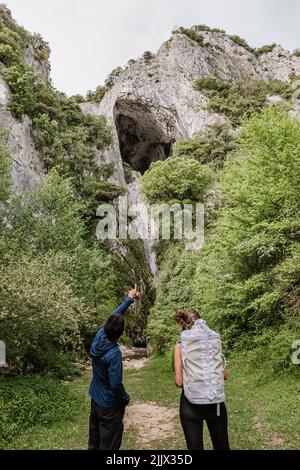Mann, der einer Freundin felsige Klippen zeigt, während sie während des Wanderns im Wald steht Stockfoto