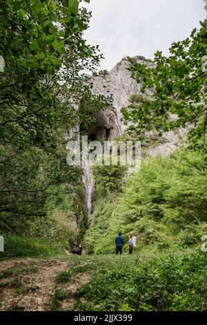 Mann, der einer Freundin felsige Klippen zeigt, während sie während des Wanderns im Wald steht Stockfoto