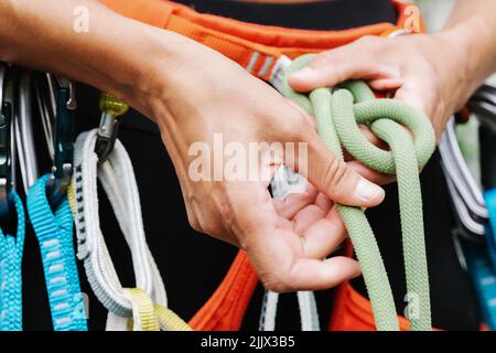 Mittelteil der weiblichen Wandererin, die während der Vorbereitung auf das Abseilen einen Seilgurt bindet Stockfoto