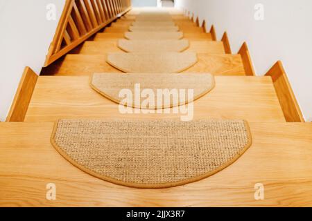 Von oben führt eine Holztreppe zum Flur eines modernen Hauses mit weißen Wänden am Tag Stockfoto