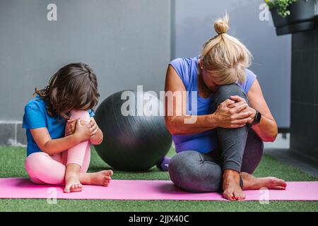 Großmutter und Enkelin praktizieren Yoga auf der Übungsmatte zu Hause Stockfoto