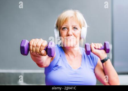 Fit Senior Frau Training mit lila Kurzhanteln, die aktiven Lebensstil Stockfoto