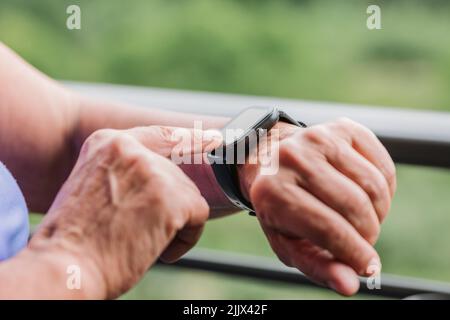 Hände einer älteren Frau, die die Fitness-Smartwatch vor dem Training aufsetzt Stockfoto