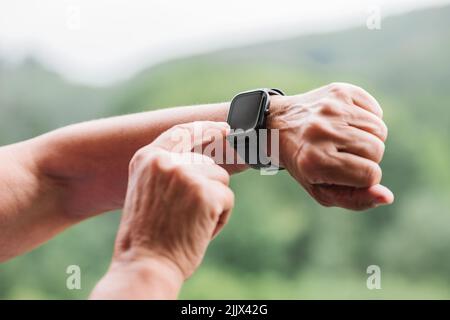 Hände einer älteren Frau, die die Fitness-Smartwatch vor dem Training aufsetzt Stockfoto