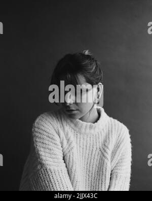 Analoges Schwarz-Weiß-Portraitfoto der ruhigen Frau, die auf dem Studiohintergrund wegschaut Stockfoto