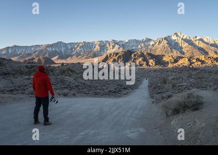 Ganzkörper-Rückansicht eines anonymen Fotografen, der die Kamera auf einer leeren Straße hält, während er die schroffen Felsklippen in Nat bewundert Stockfoto