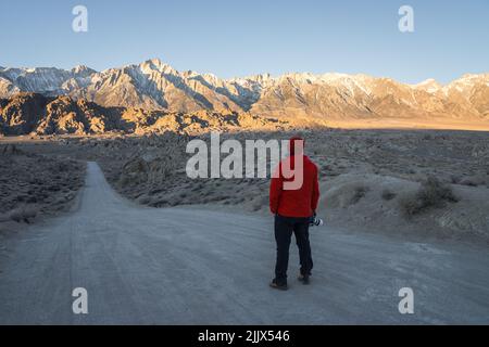 Ganzkörper-Rückansicht eines anonymen Fotografen, der die Kamera auf einer leeren Straße hält, während er die schroffen Felsklippen in Nat bewundert Stockfoto