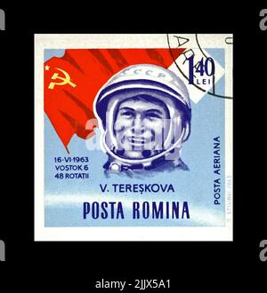 Valentina Tereshkova, sowjetische Astronautin, 1. Frau im Weltraum, rote sowjetische Flagge, um 1963. Abgesagte Briefmarke gedruckt in Rumänien isoliert auf Blac Stockfoto