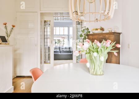 Moderner Speisesaal mit Blumenstrauß in Vase auf dem Tisch zu Hause an einem hellen Tag Stockfoto