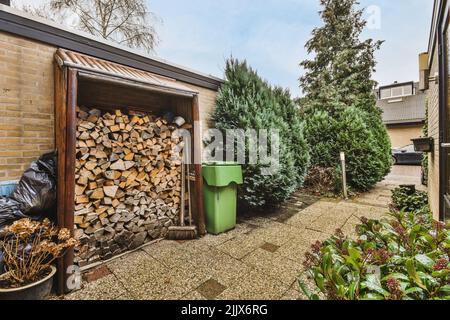 Hinterhof eines Hauses mit Brennholzlager und Bäumen und grünen Pflanzen Stockfoto