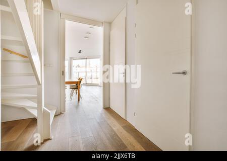 Treppe in hellem Flur mit weißem Boden und Wänden an sonnigen Tagen in modernem Haus Stockfoto