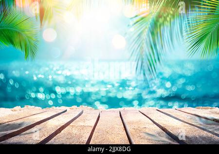 Sommertisch Und Meer Mit Verschwommenen Blättern, Palme Und Unschärfe Bokeh Light On Ocean - Holzplanke In Abstrakter Landschaft Stockfoto