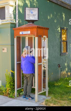 Langley, WA, USA - 25. Juli 2022; Person, die 2022 an einer Stand-alone-Telefonzelle in Langley, Washington, die betriebsbereite Whidbey Telecom-Telefonzelle verwendet Stockfoto