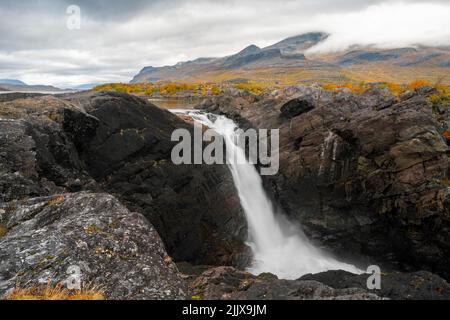 Mächtiger landschaftlicher Wasserfall unter dramatischem Himmel. Stuor Muorkke Wasserfall im Stora Sjofallet Nationalpark, Schweden. Abenteuer in arktischer Wildnis. Herbst Stockfoto