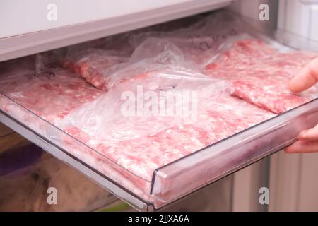 Ein Mann legt Hackfleisch und Rindfleisch in den Gefrierschrank in Servierbeutel für lange Lagerung. Stockfoto