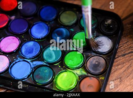 Palette von Aquarellfarben und Pinsel auf einer hölzernen Oberfläche.Draufsicht. Stockfoto